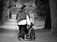 Woman walking away from camera while pushing wheelchair
