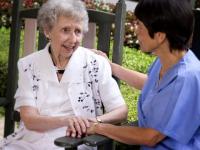 Female nurse sitting with elderly woman outdoors