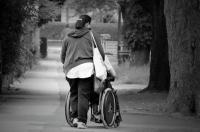 Woman walking away from camera while pushing wheelchair